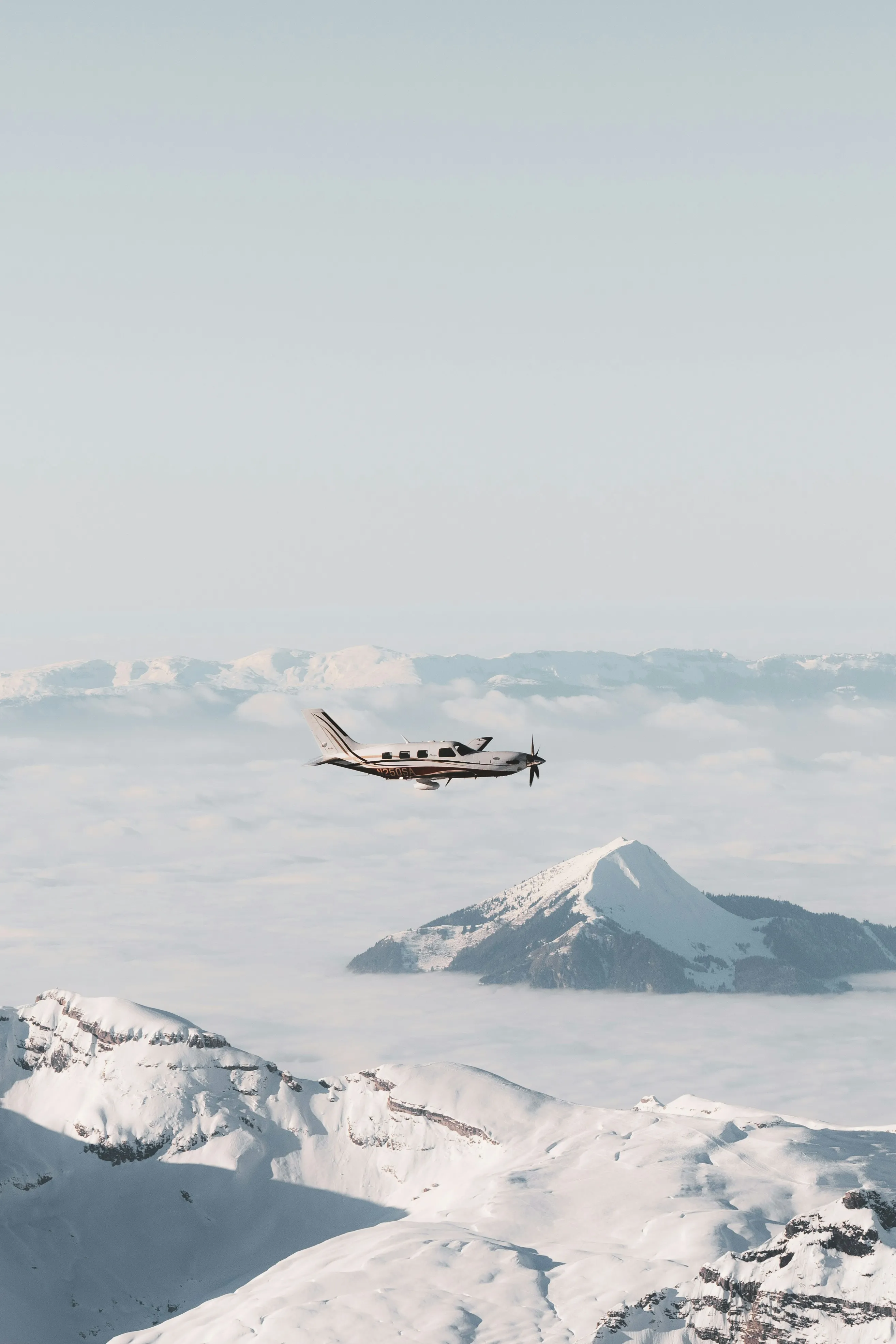 Aircraft flying over snow covered mountain peaks