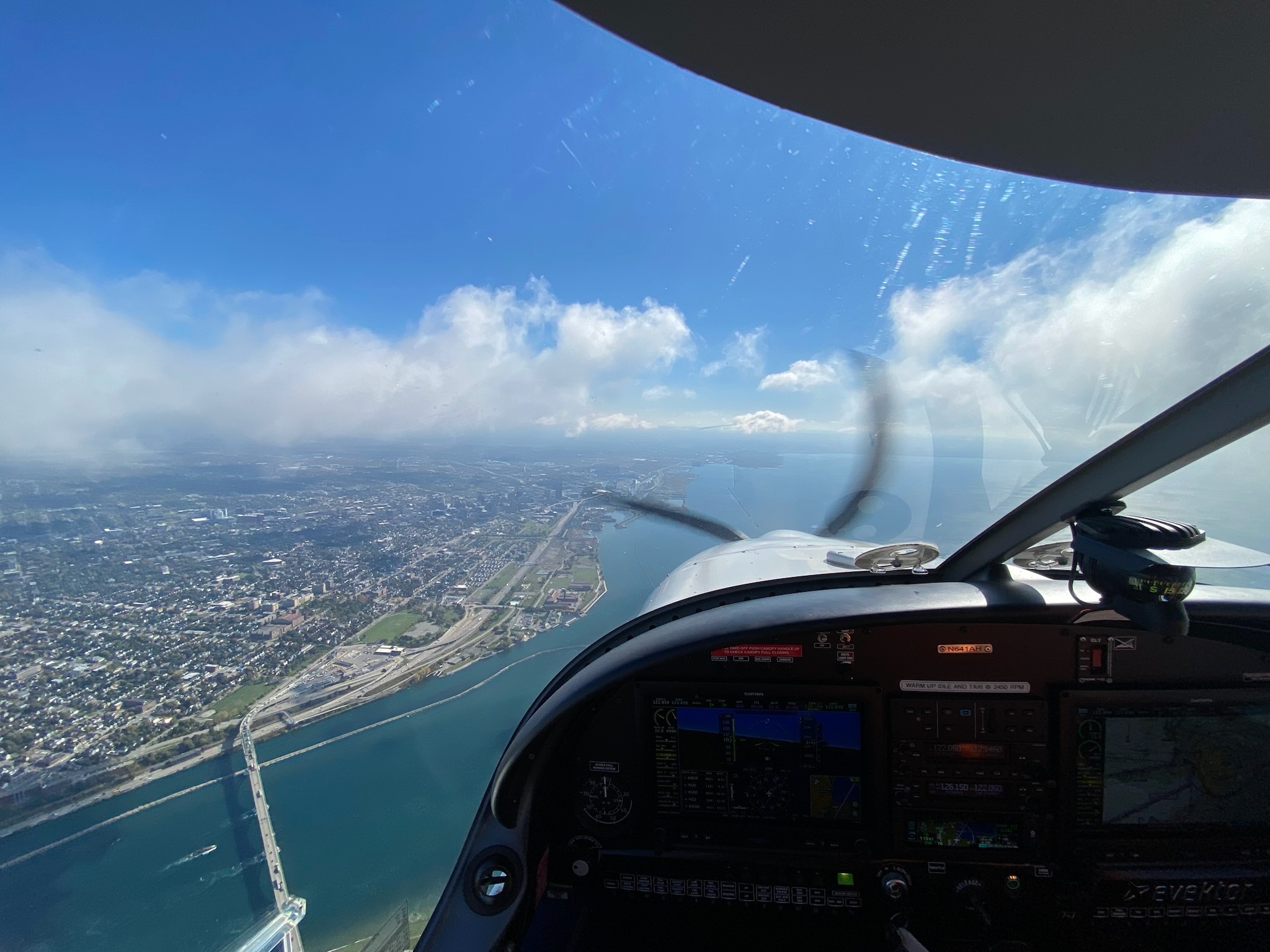 View through a training aircraft windshield during a flight above a city and shoreline