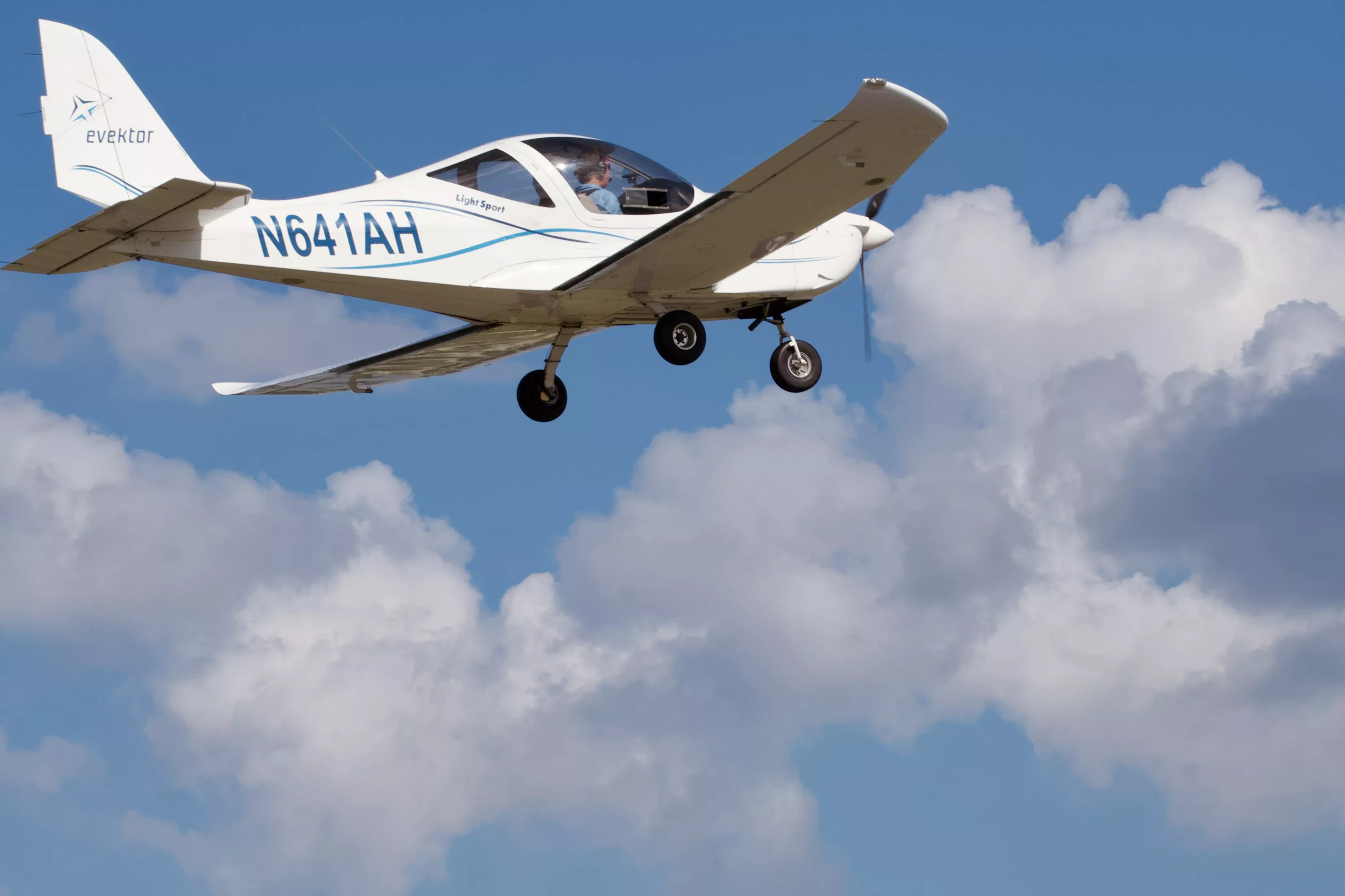 Evektor Harmony training aircraft flying against a blue sky and clouds