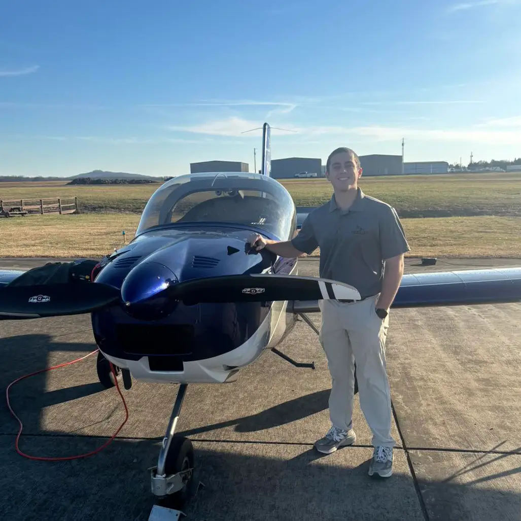 Christian Rosa standing beside the nose and propeller of a blue Hawkins Flight Academy RV-12 on the ramp at Shelbyville