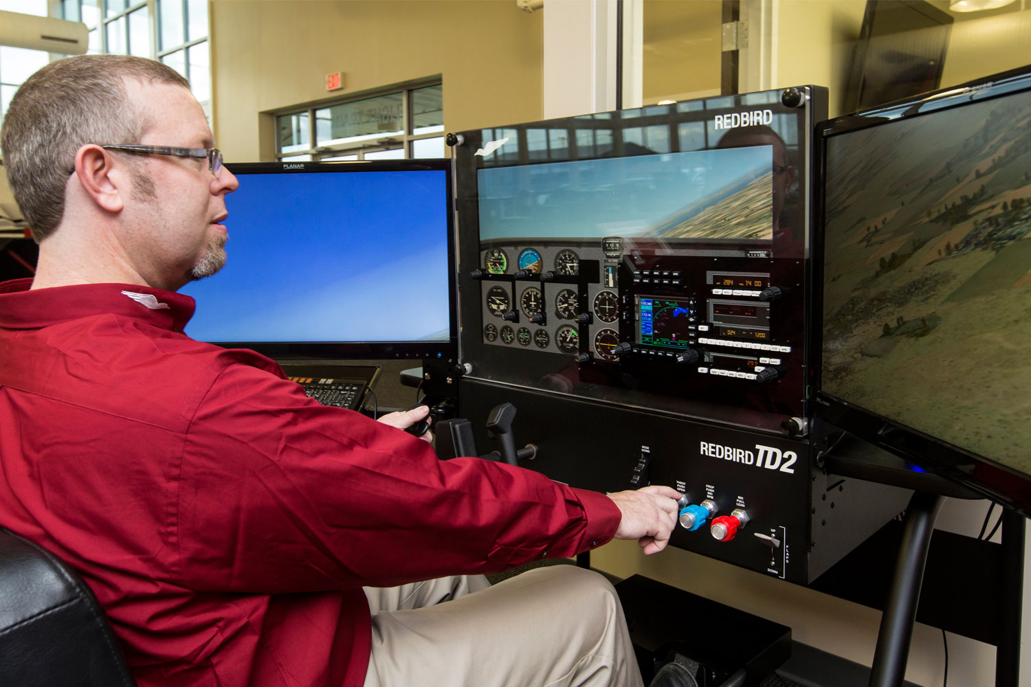 Adult student practicing flight procedures in a Redbird TD2 training device